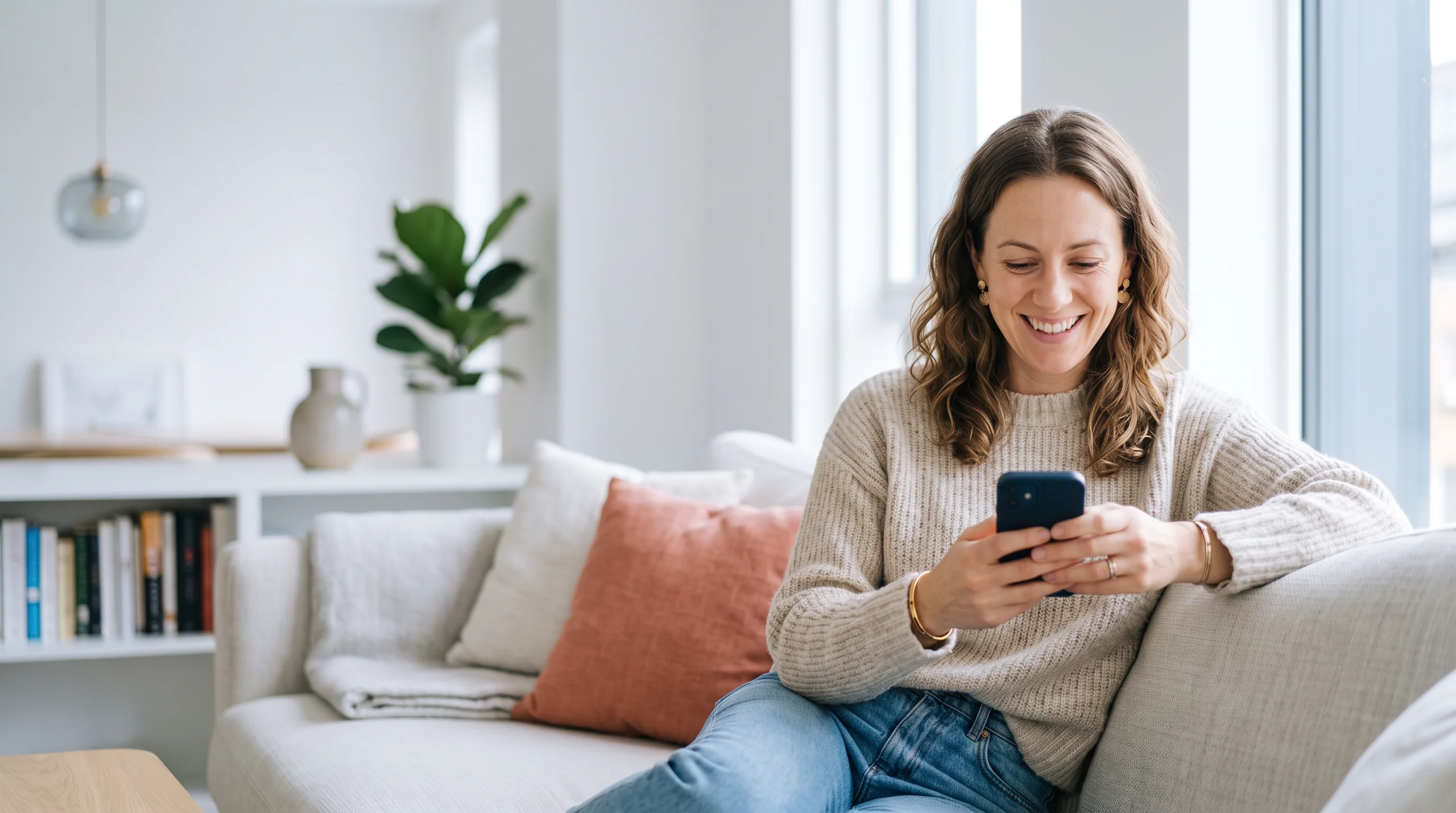 Woman smiling at her phone on the couch